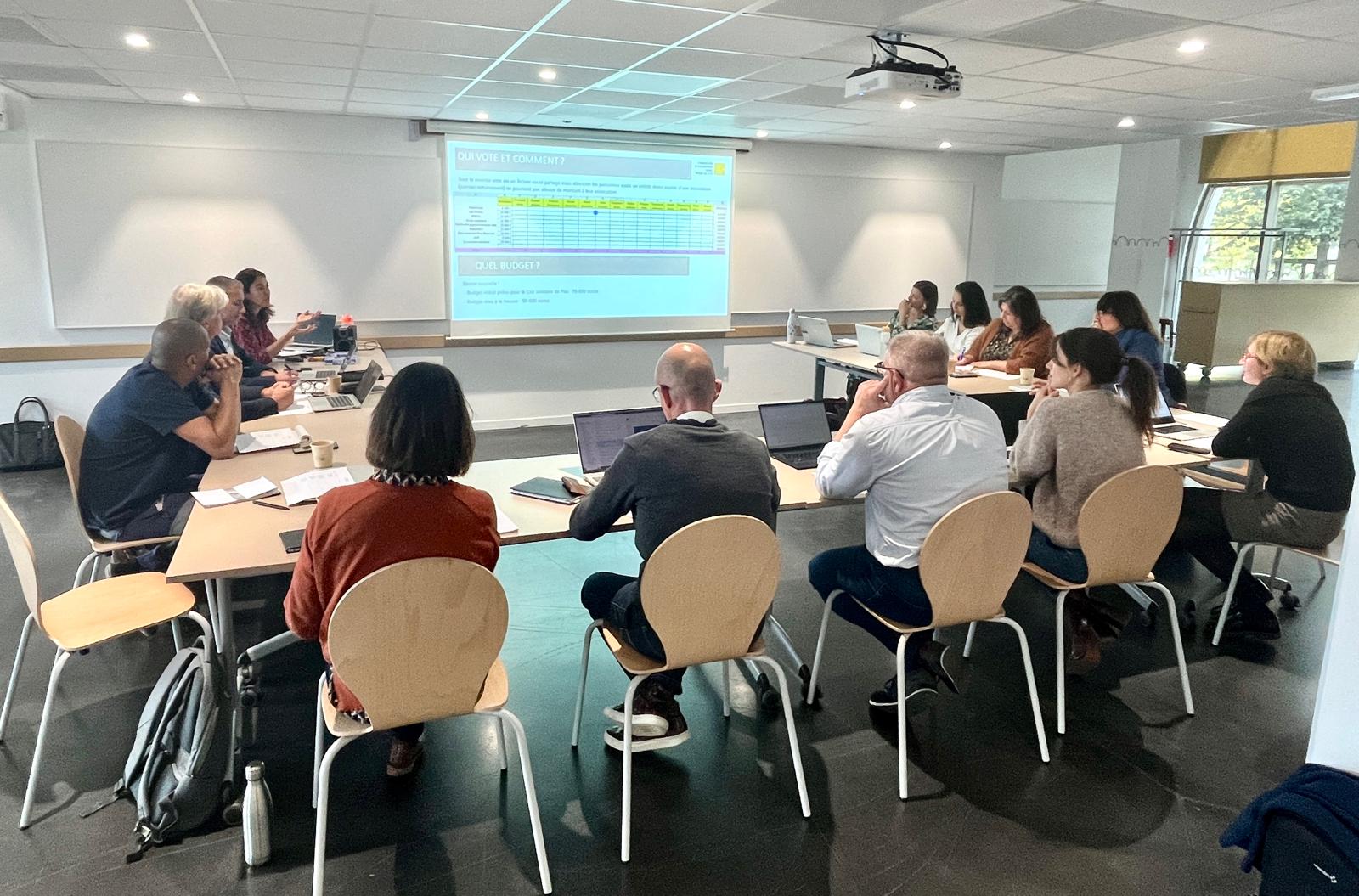 Personnes autour de tables réfléchissant devant un tableau Excel